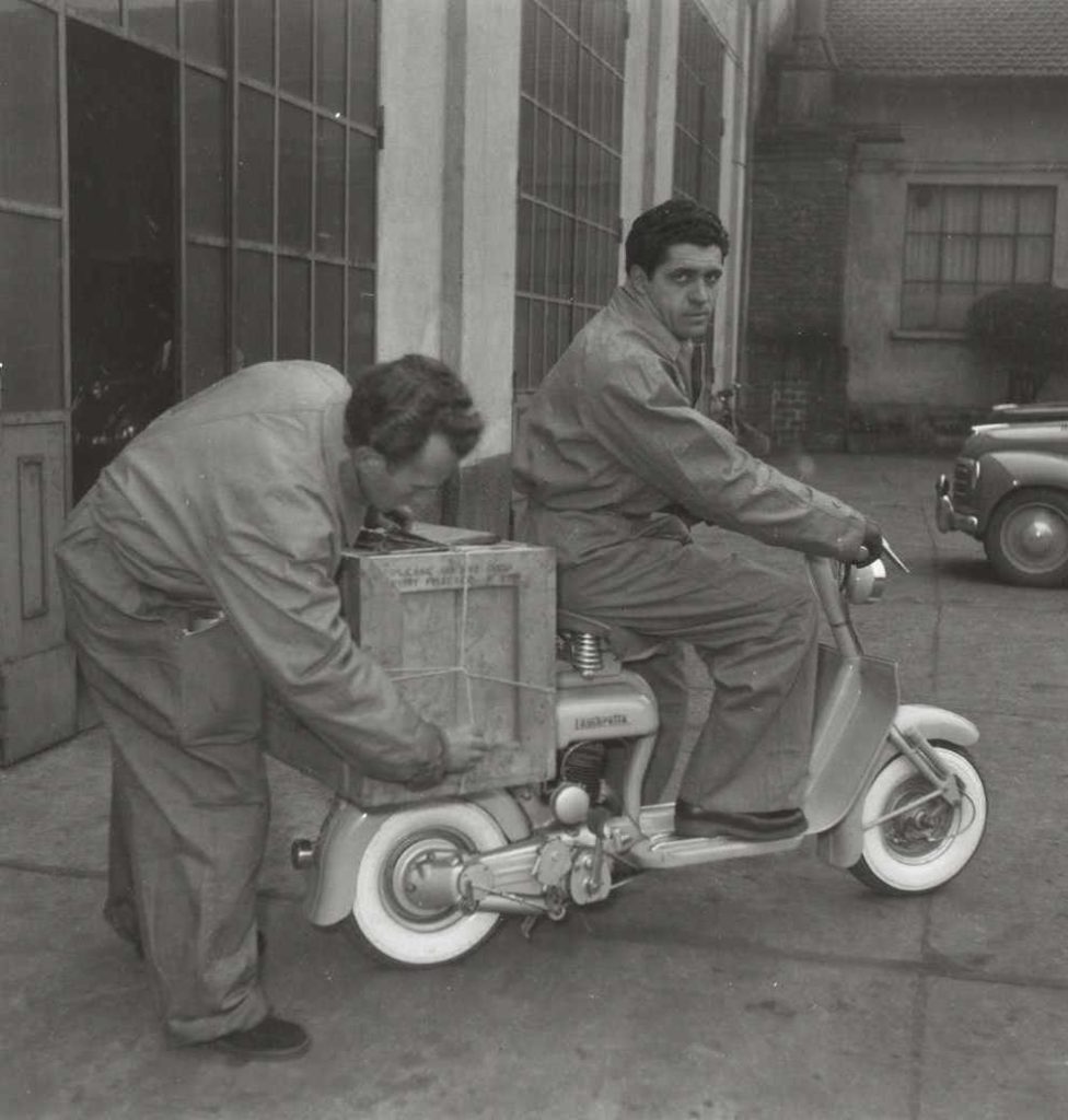 1950 man placing box on Lambretta scooter with another man on it