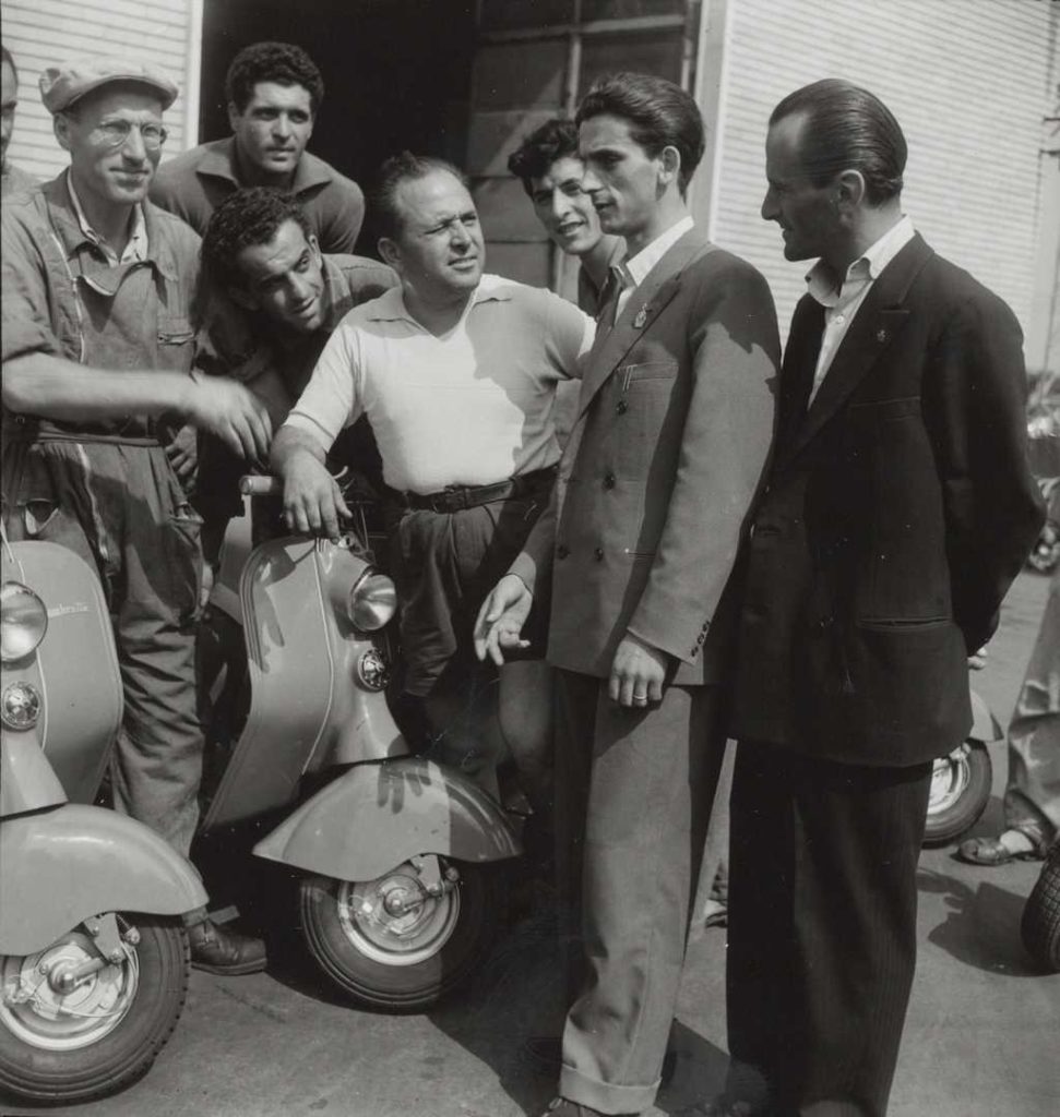 Motorcycle road racer Umberto Masetti watching Lambretta scooters